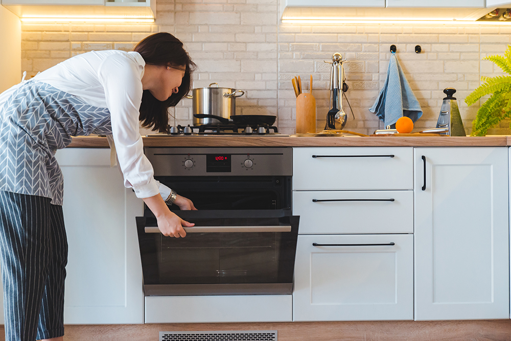 young woman open oven to cook with propane